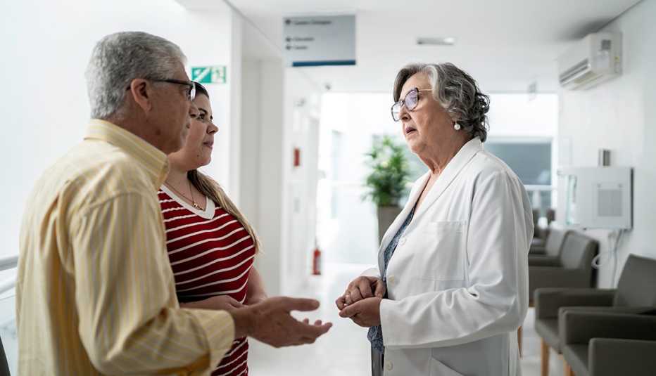 doctor in a hospital talking to a man and his daughter