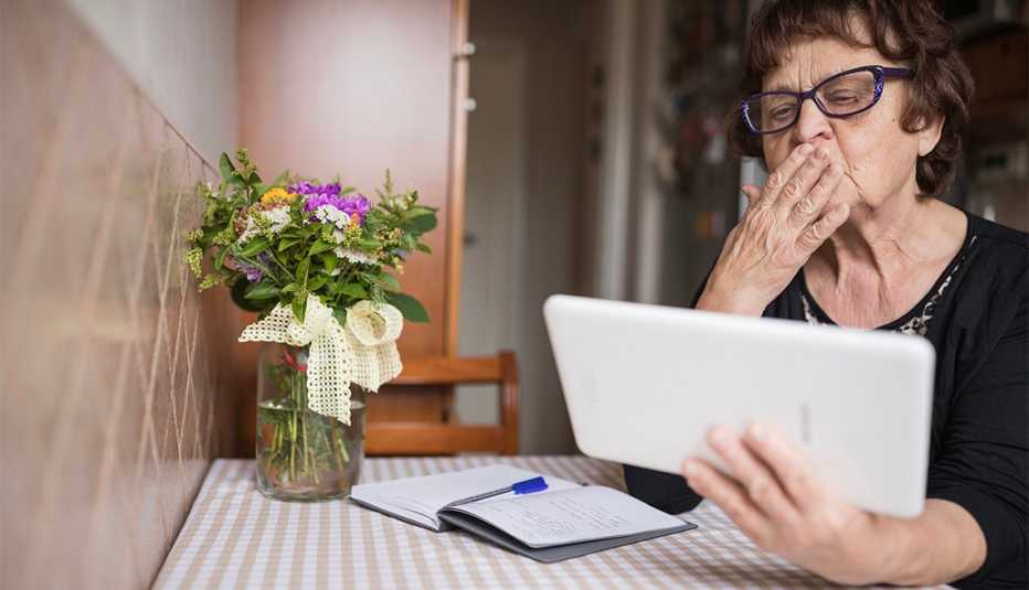a woman using a tablet for a video call blowing a kiss