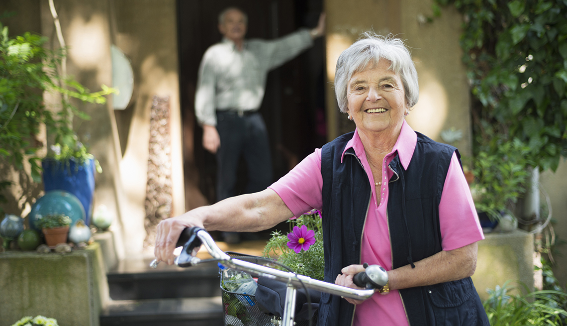 A woman holding a bike with a man in the background of the doorway