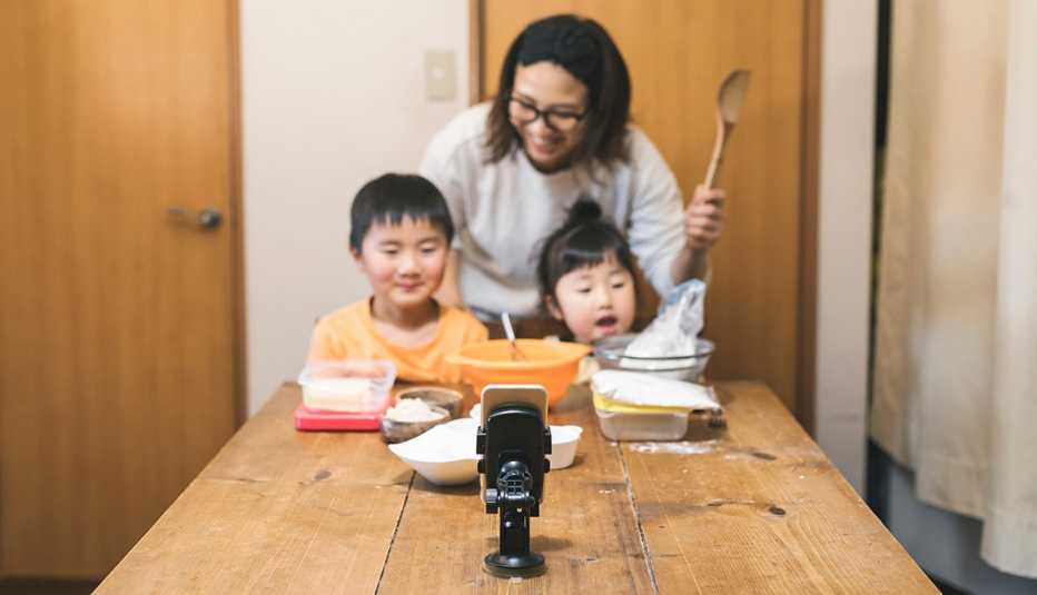 A mom and her two children baking holiday cookies with their grandmother using video chat on a mobile phone A mom and her two children baking holiday cookies with their grandmother using video chat on a mobile phone