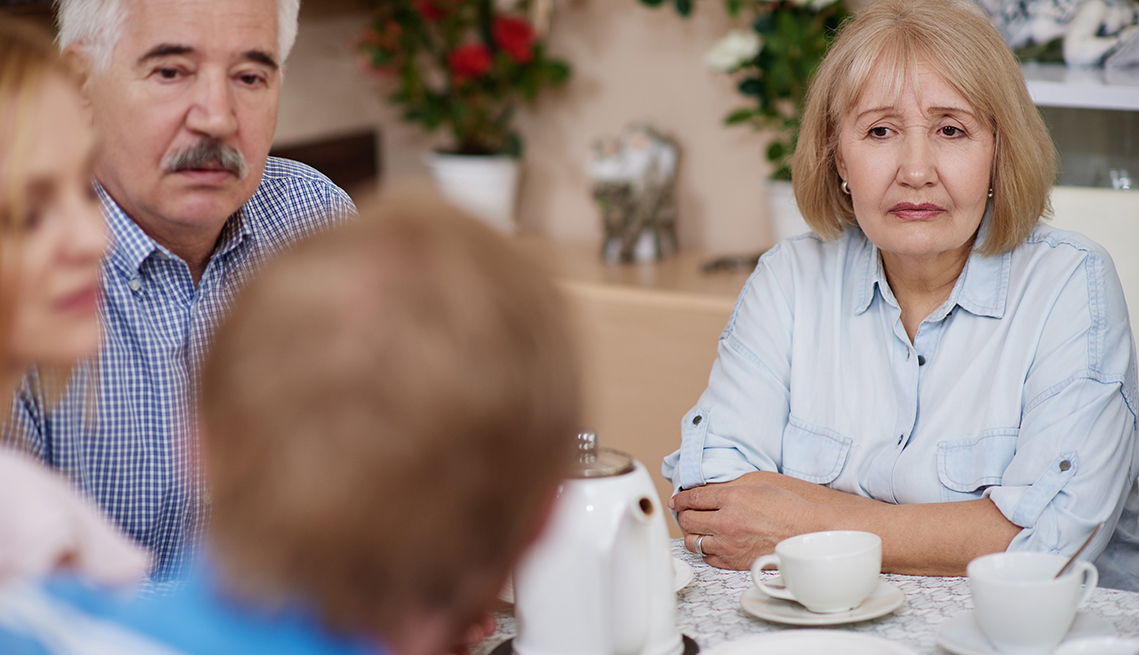 Group of four adult siblings sitting at a table having a serious conversation