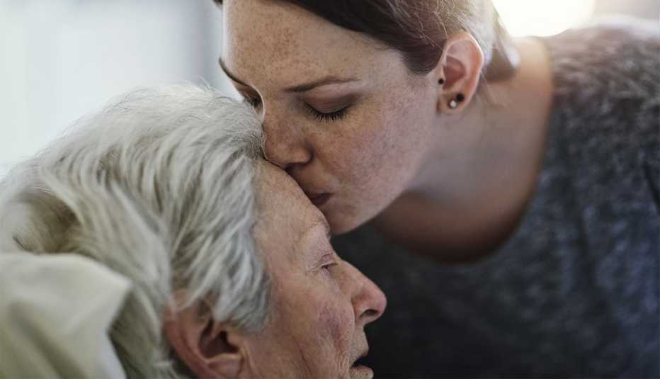 a woman kissing her mother on the forehead
