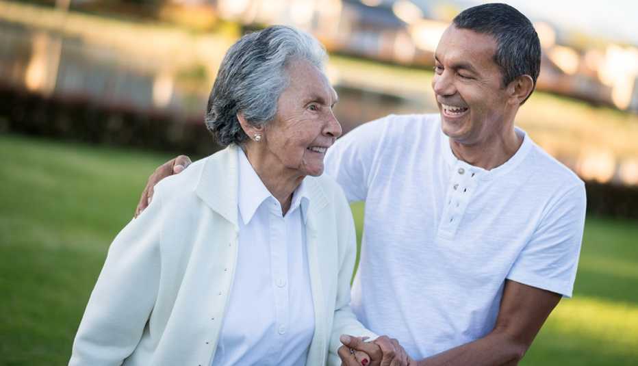 Older woman walking outside with the assistance of her son
