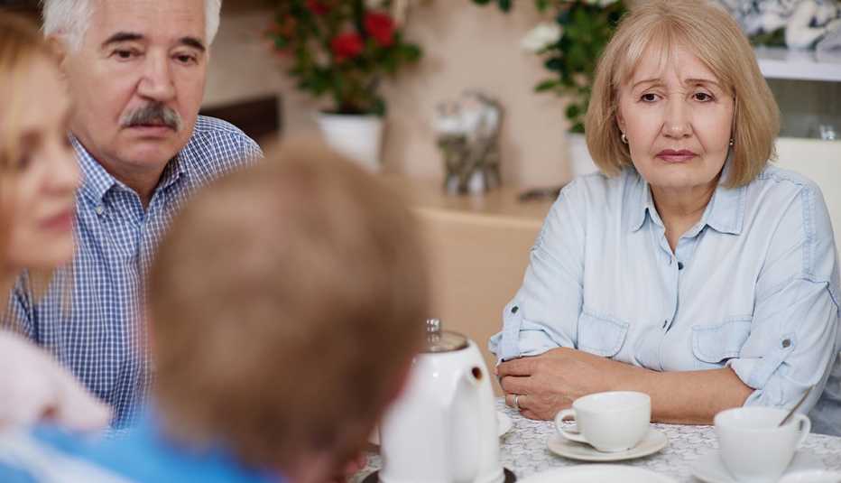 Group of four adult siblings sitting at a table having a serious conversation