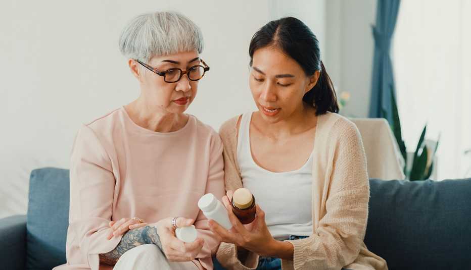Adult daughter looks at medication bottles with her mother