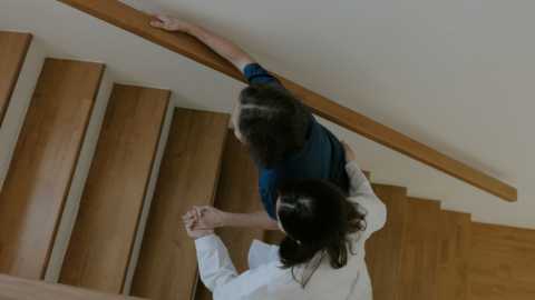 a woman guides another woman up a flight of stairs