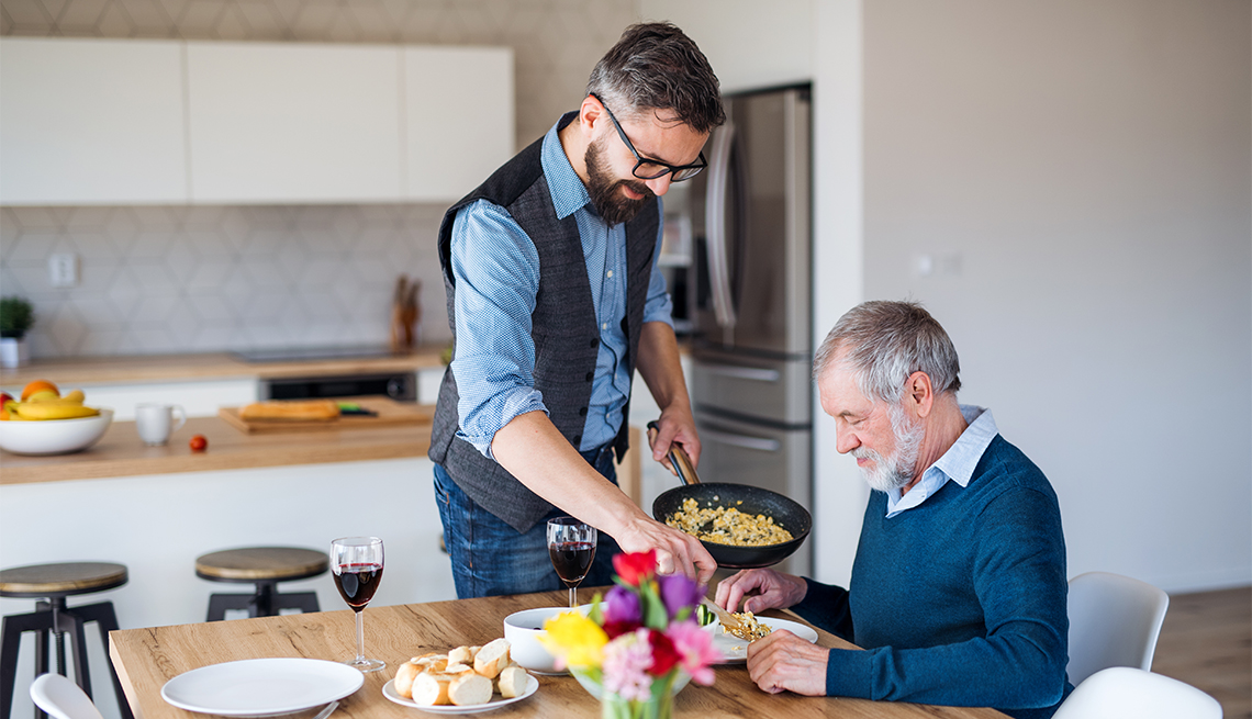 a man caregiving for his father serving him dinner