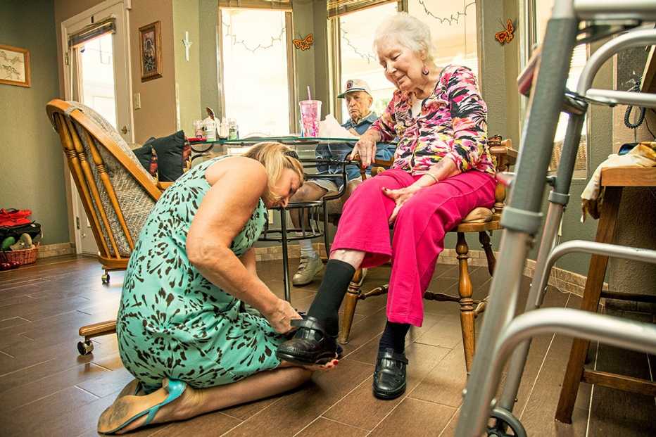amy goyer helping her mother don her shoes as her father watches