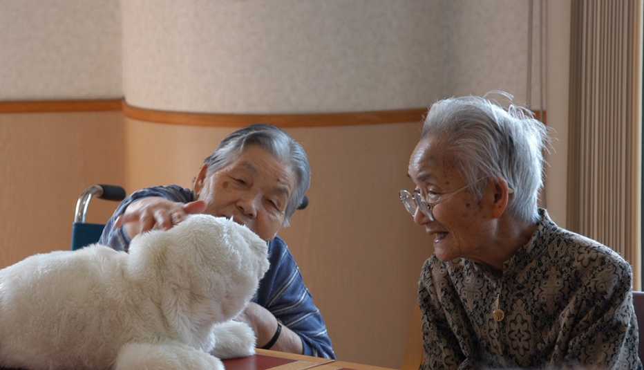 Two women petting Paro seal robot