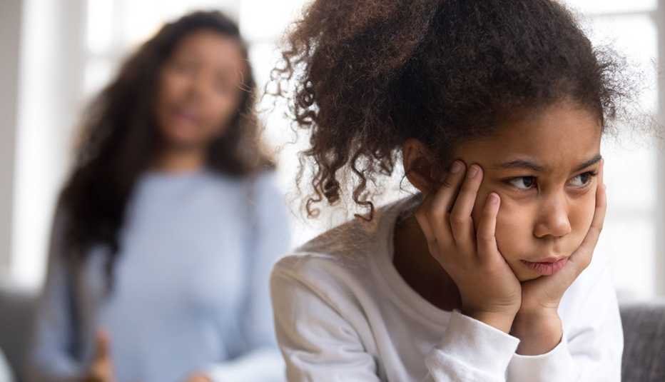 A young child looks off into the distance with their mom talking behind them A young child looks off into the distance with their mom talking behind them