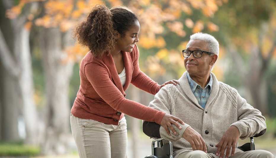 Woman caregiver pushes man in a wheelchair