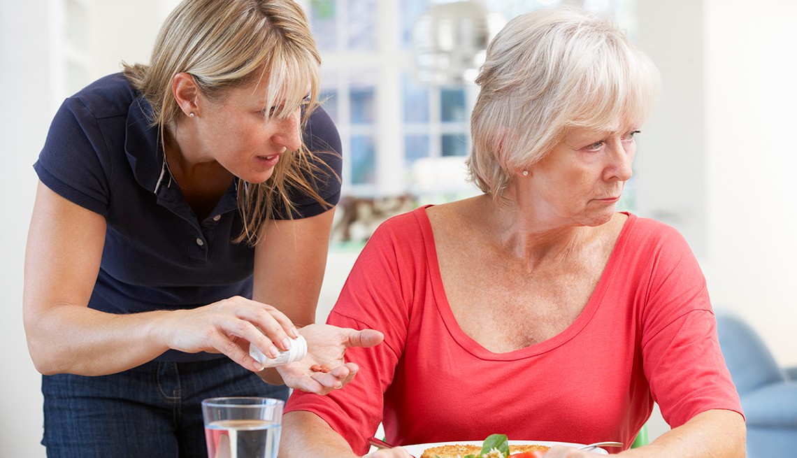 Older woman looking angry and refusing medication from her daughter. Older woman looking angry and refusing medication from her daughter.