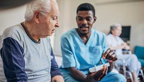 nurse arranging medical tablets in a daily pill box for man nurse arranging medical tablets in a daily pill box for man