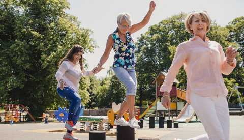 senior women balance on playground stepping stones  senior women balance on playground stepping stones