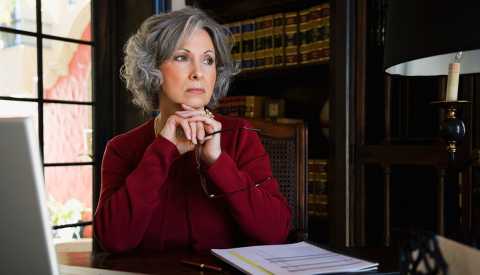 Woman sitting at desk contemplating advanced directives forms Woman sitting at desk contemplating advanced directives forms