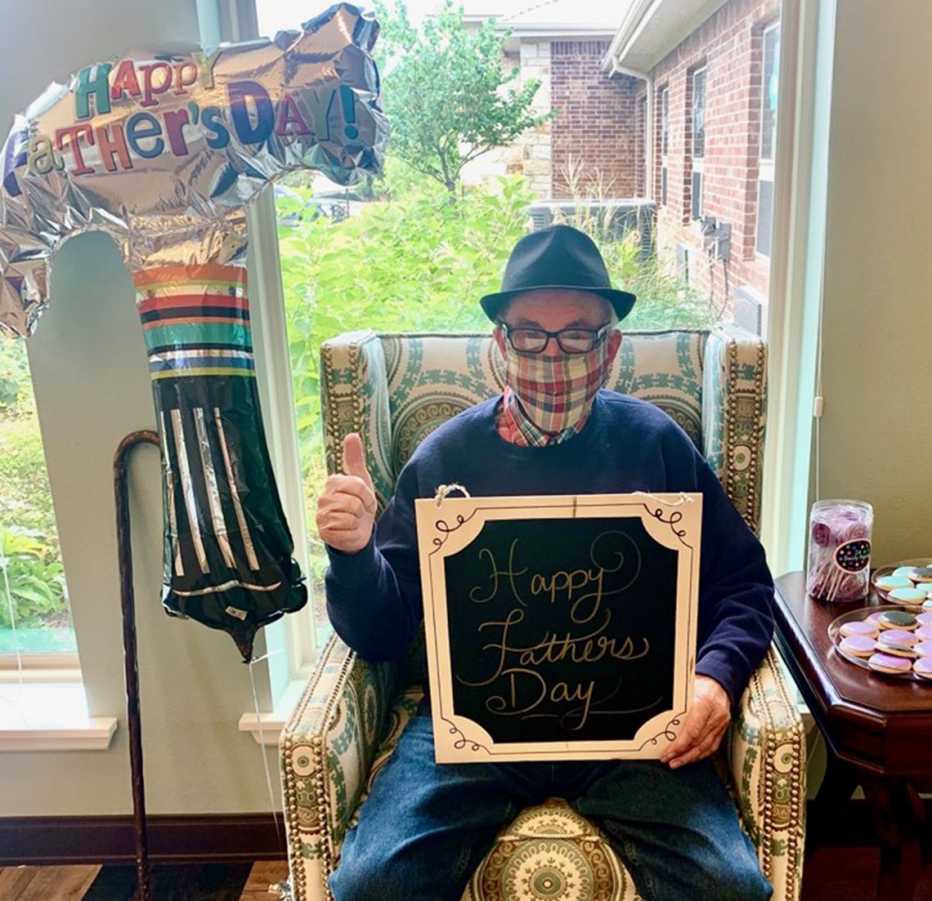 Richard wearing a face mask and holding a sign that says happy fathers day 