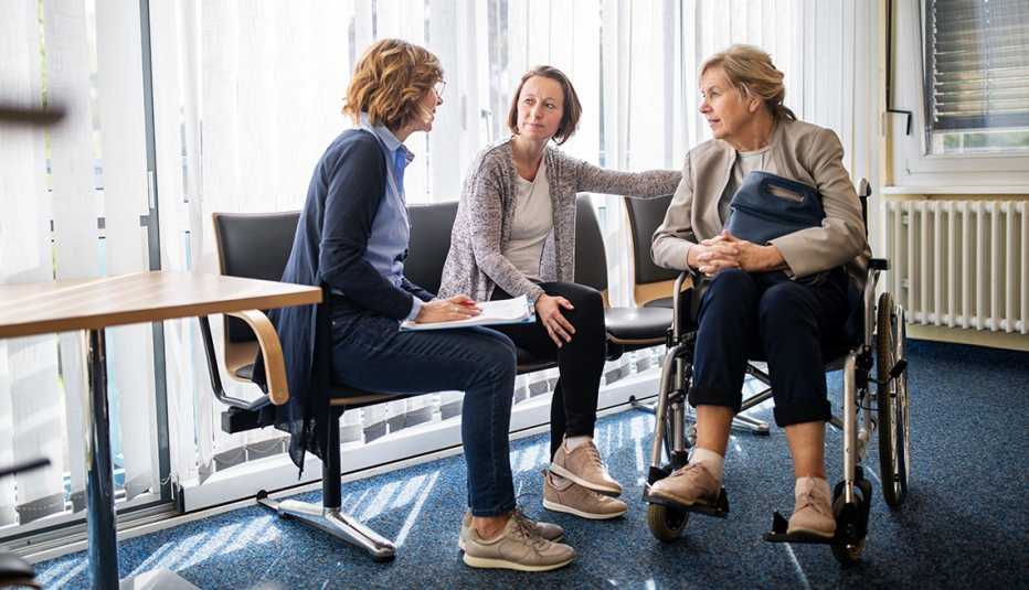 A doctor having a discussion with a woman in a wheelchair and her adult daughter