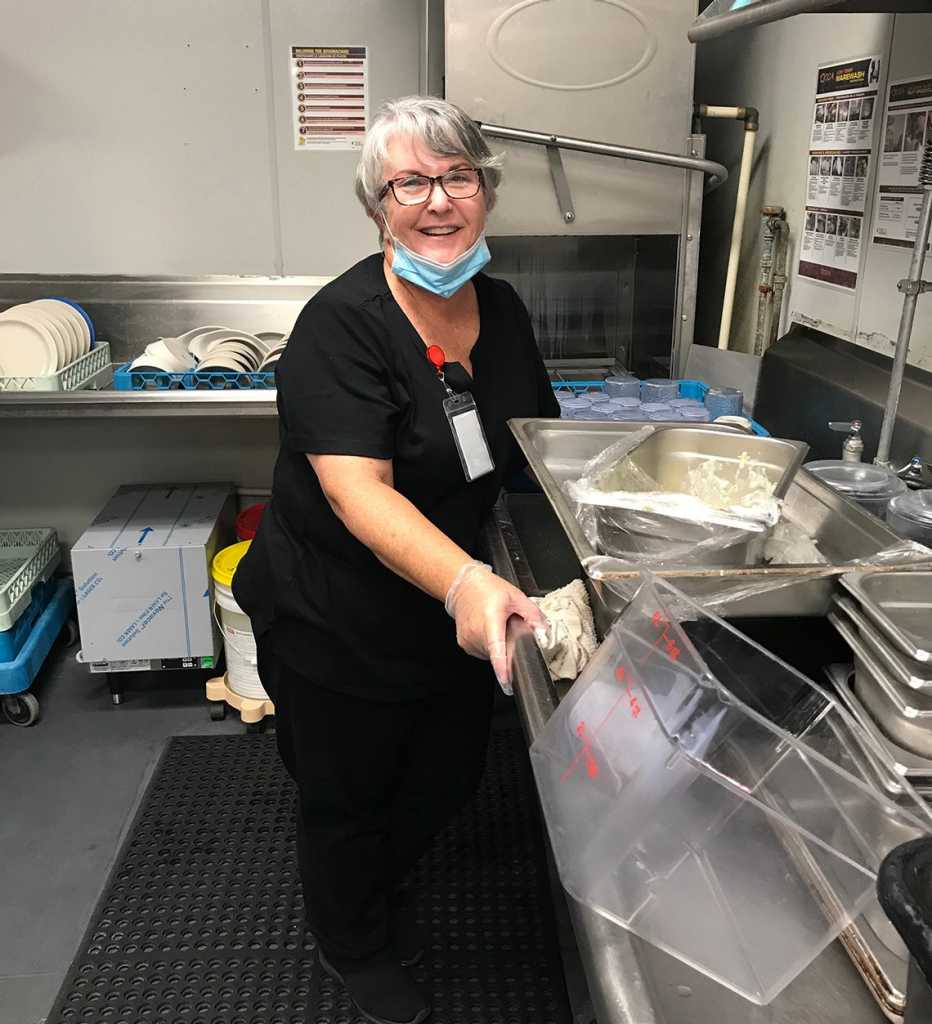 Woman washing dishes in a nursing home kitchen.