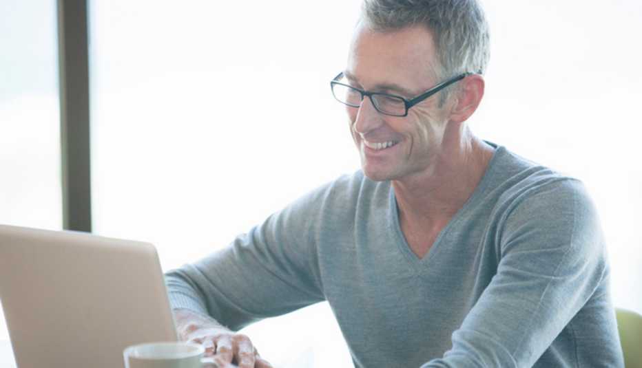 Man using a laptop holding a cup of coffee