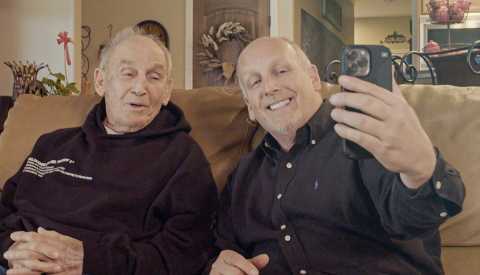 Ed and Dan Salinger sitting on a couch as they film a video on a smartphone Ed and Dan Salinger sitting on a couch as they film a video on a smartphone