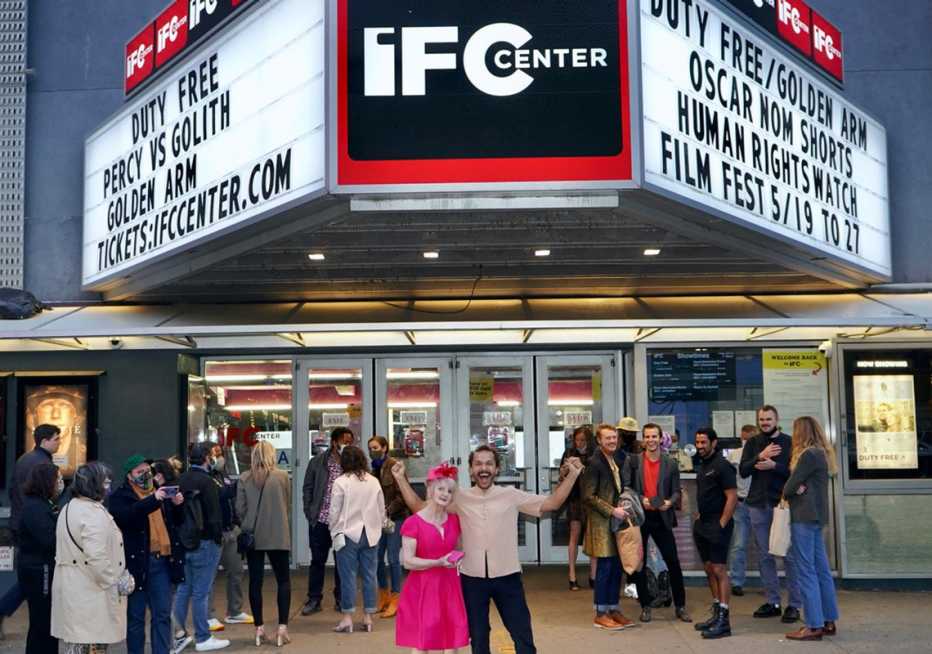 Sian-Pierre Regis and Rebecca Danigelis in front of a theater marquee promoting duty free