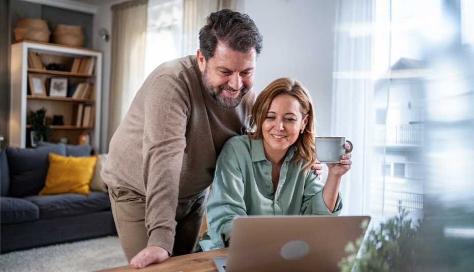 AARP member couple checking their email together on a laptop in thier living room