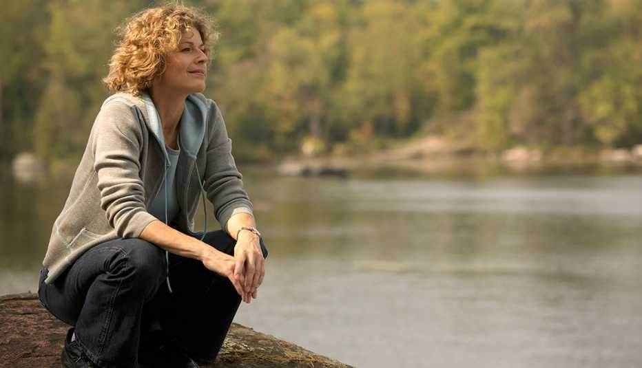 A woman kneeling down near lake