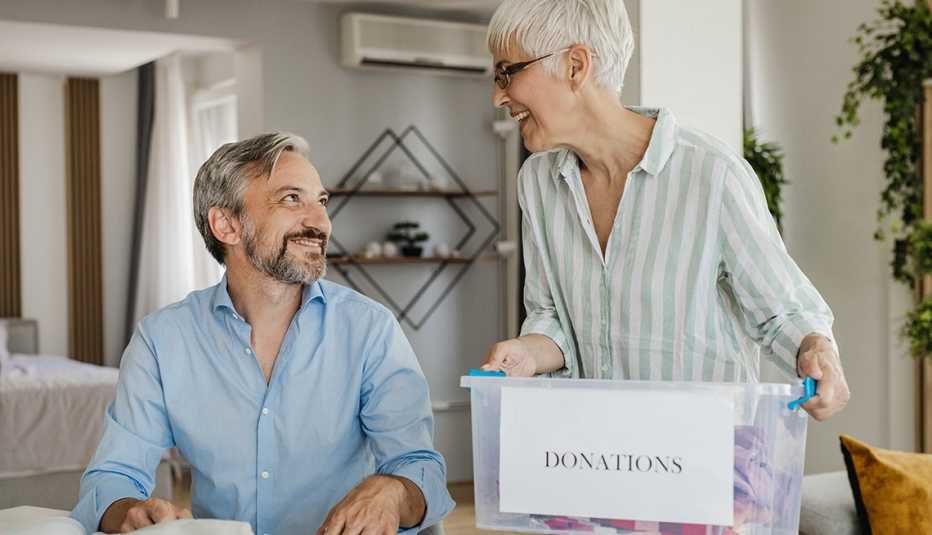 A couple preparing a box full of clothes for a donation A couple preparing a box full of clothes for a donation