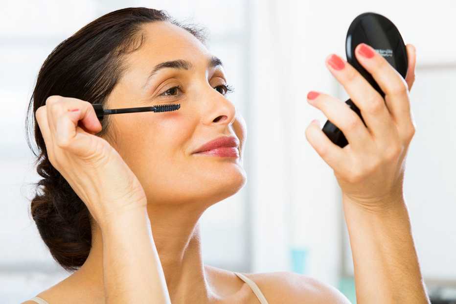a woman applying makeup on her eyes