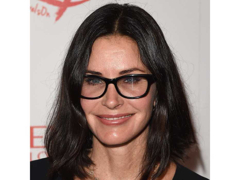 Courteney Cox wearing black frame glasses.