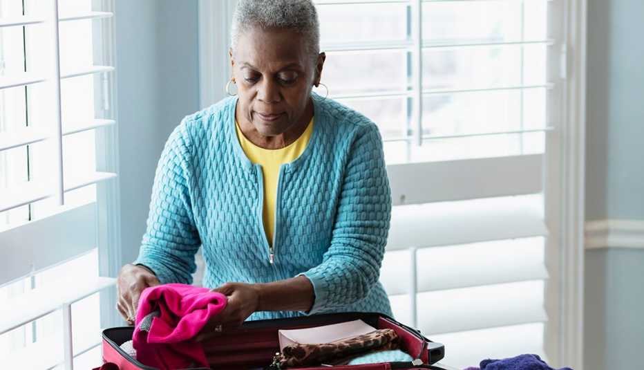 A woman at home packing a suitcase for a trip