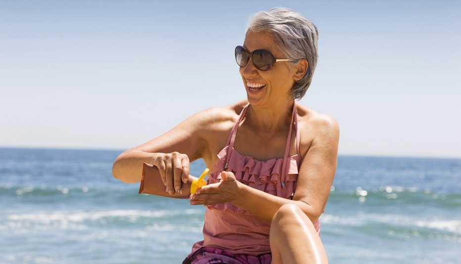 A woman applying sunscreen at the beach