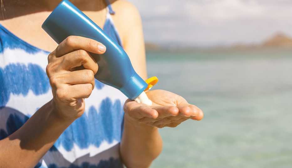 A woman pouring sunscreen lotion out of a bottle and into her hand