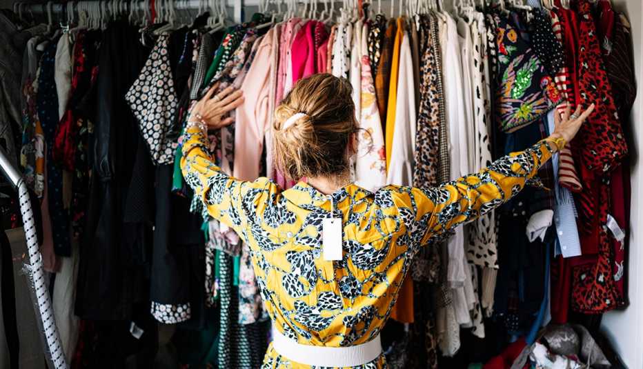 A woman in a yellow dress with its price tag looking at a closet full of clothes