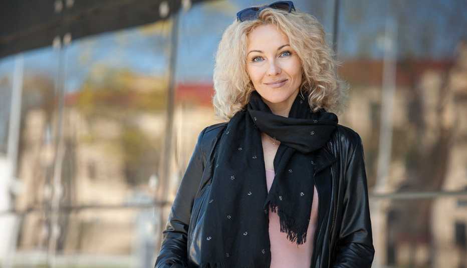 Woman with curly hair in a black leather jacket, black scarf and sunglasses on top of her head