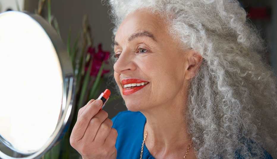 a woman applying lipstick in a mirror a woman applying lipstick in a mirror