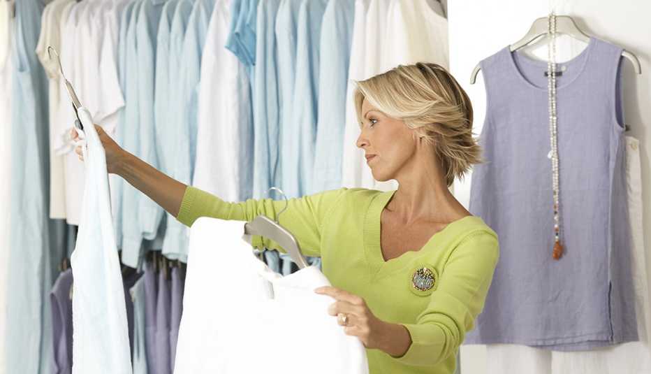 A woman shopping in clothes shop comparing two tops on coathangers A woman shopping in clothes shop comparing two tops on coathangers