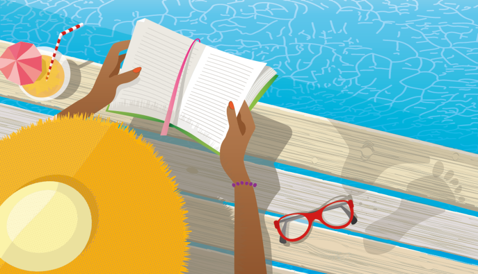a woman on a deck by a pool wearing a sun hat reading a book