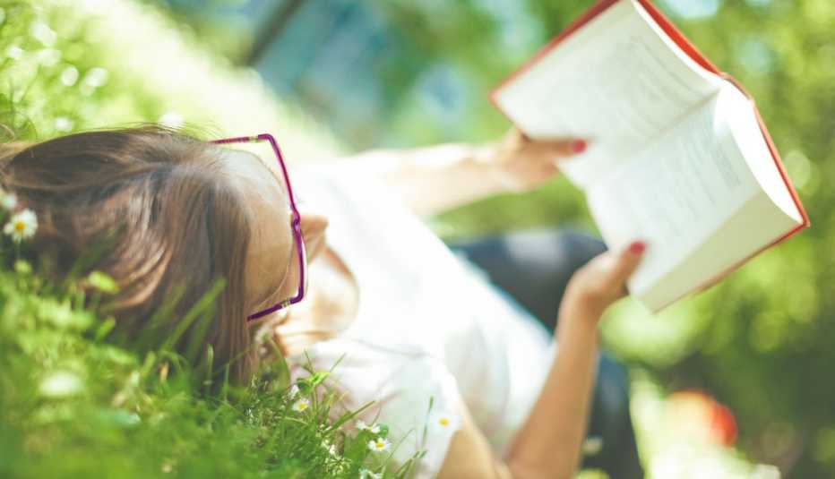 woman reads book on the grass