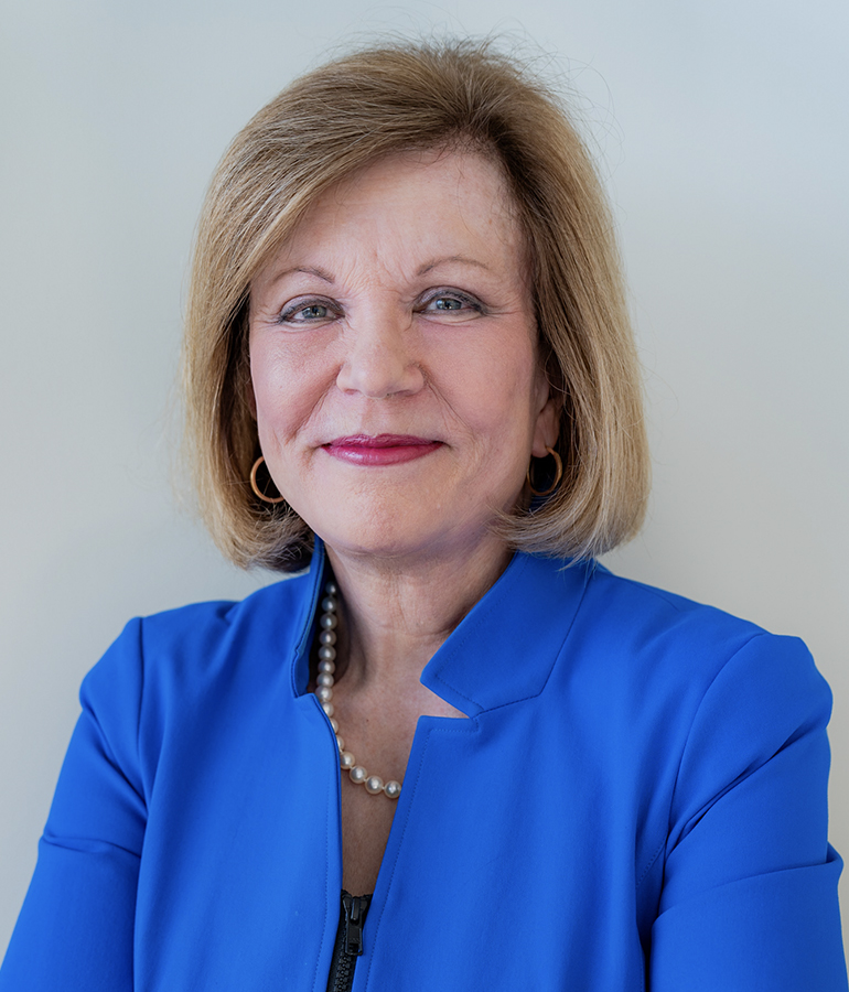 Susan Page smiling in front of light gray background