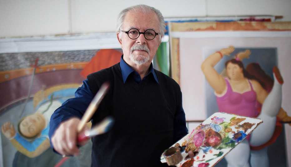 Colombian painter and sculptor Fernando Botero in his studio with brushes and palette in his hands. colombian artist fernando botero in his art studio with brushes and a palette in his hand