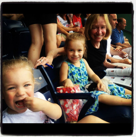 family photo taken at a baseball stadium up close of two small children and their grandmother 