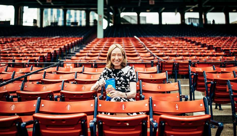 doris kearns goodwin sits in the stands of an empty baseball stadium holding a bag of peanuts