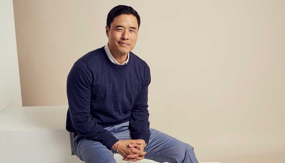 randall park sitting on white step against off white background