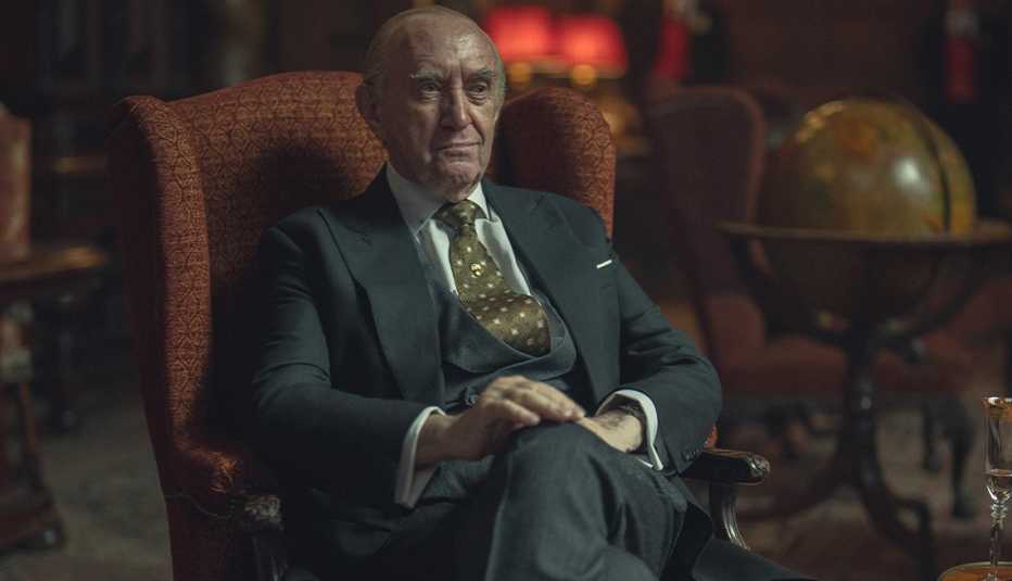 Jonathan Pryce on "The Crown" jonathan pryce sitting in chair in a still from the crown
