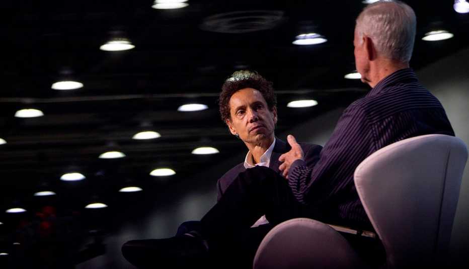 malcolm gladwell sitting next to man under lights