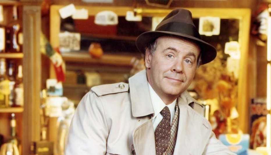 Tim Conway, US actor and comedian, wearing a beige overcoat over a tweed jacket, a white shirt and brown tie, with a brown fedora with a black band, leaning on the back rest of a chair in a studio portrait, circa 1975. Tim Conway, US actor and comedian, wearing a beige overcoat over a tweed jacket, a white shirt and brown tie, with a brown fedora with a black band, leaning on the back rest of a chair in a studio portrait, circa 1975.