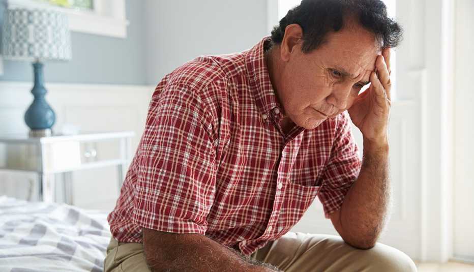 Man Sitting On Bed Suffering With Depression