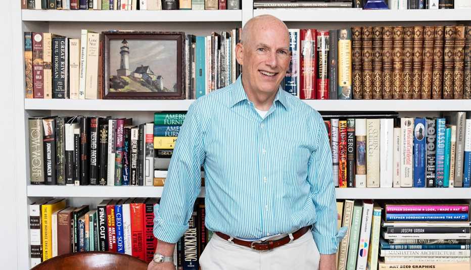 scott manning smiles at the camera in front of a full bookcase at his home