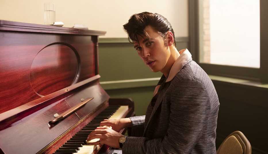Austin Butler sitting in front of a piano for a promotional photo for the film Elvis
